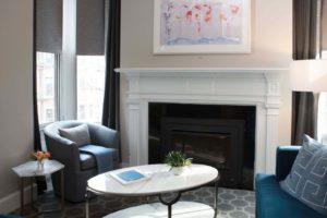 Warm and inviting sitting area with a fire place and artwork in the living room of the queen suite